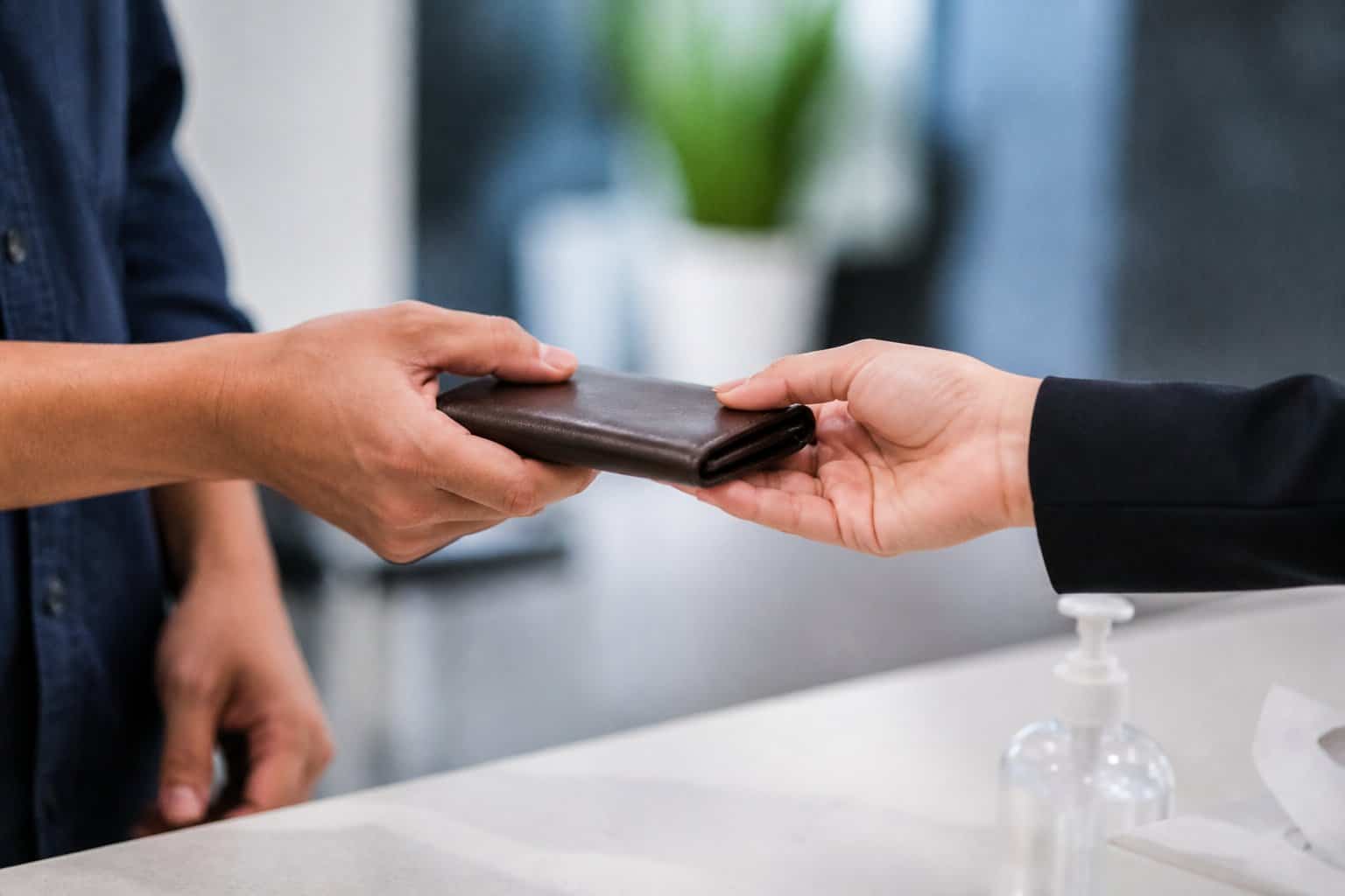 Two people exchanging a small personal item with a focus on their hands in a clean indoor setting.
